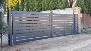 a gate with a cement wall and a tree